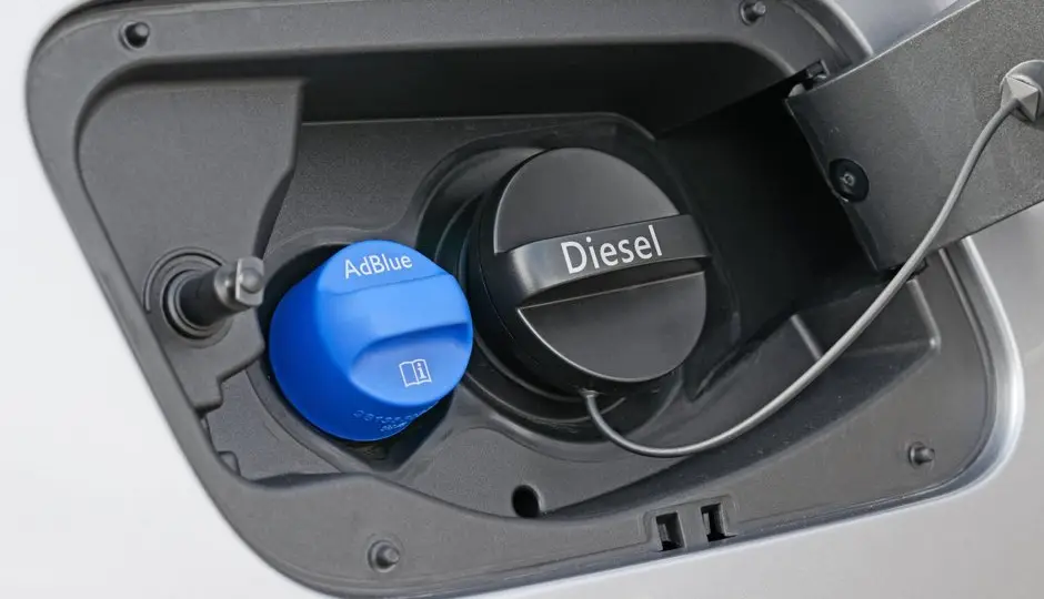 Bidon d'AdBlue posé près du bouchon de remplissage bleu d'un véhicule diesel équipé d'un système SCR