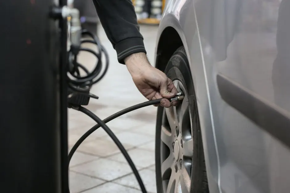 Gonfleur pneu voiture portable avec manomètre numérique posé près d'une roue